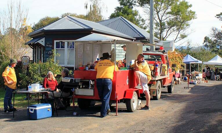 Rural Fire Brigade helpers have a yarn before customers converge on their popular outdoor barbecue at the Wyndham Village Market.