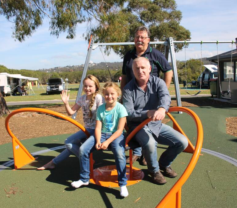 CAROUSEL: Sisters Zoe, 10, and Uma, 8, test drive new equipment in the children's playground with park manager Chris Donohue and Sapphire Coast Tourism executive director Anthony Osborne. Picture: Liz Tickner