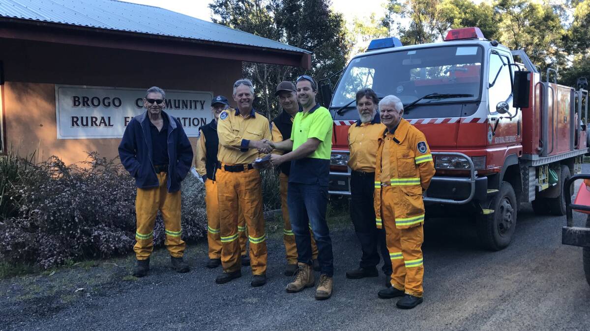 Matthew McKinnon from Cyneve presents a cheque for $1500 to Brogo RFS brigade captain Mike Jay.