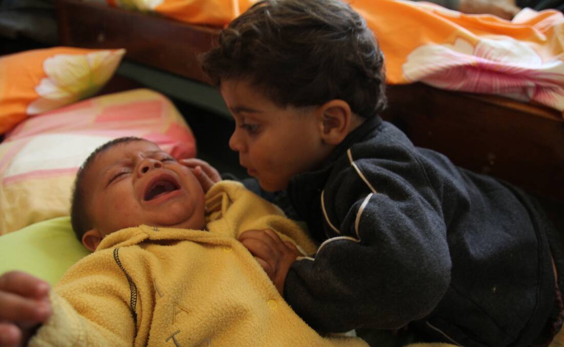CARE: A young refugee tries to sooth his sick brother on Leros. 