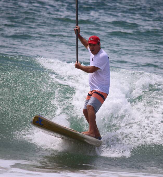 Fun ride: A surfer in the SUP relay of last year's Merimbula Classic counter-balances on his way into the beach. 