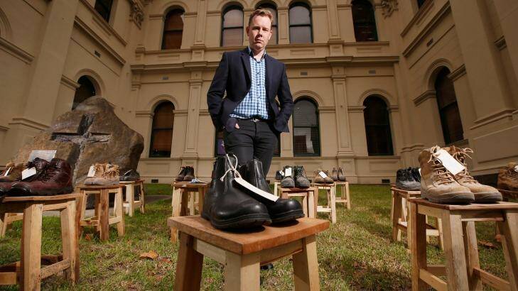  Victorian Trades Hall Council Secretary Luke Hilakari poses among the work boots symbolising workers killed on the job in the past year. Photo: Darrian Traynor