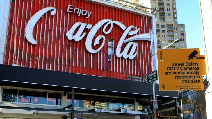 The iconic Coca-Cola sign, undergoing an update, stands amid the watchful eye of CCTV. Photo: James Alcock