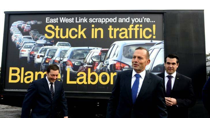 Prime Minister Tony Abbott, flanked by Victorian Opposition Leader Matthew Guy, left, and local member Michael Sukkar, stand in front of a "Blame Labor" sign. Photo: Tracey Nearmy