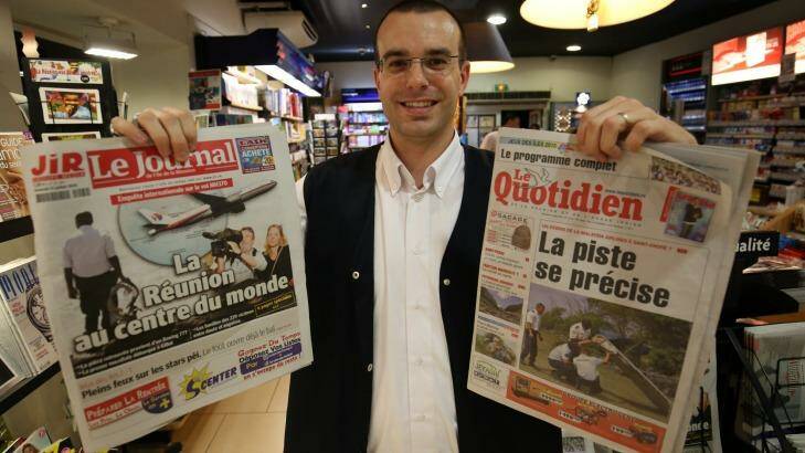 Saint-Denis newsagent owner Frederik Varin holds up the front pages of two local newspapers covering the MH370 story. Photo: Colin Cosier