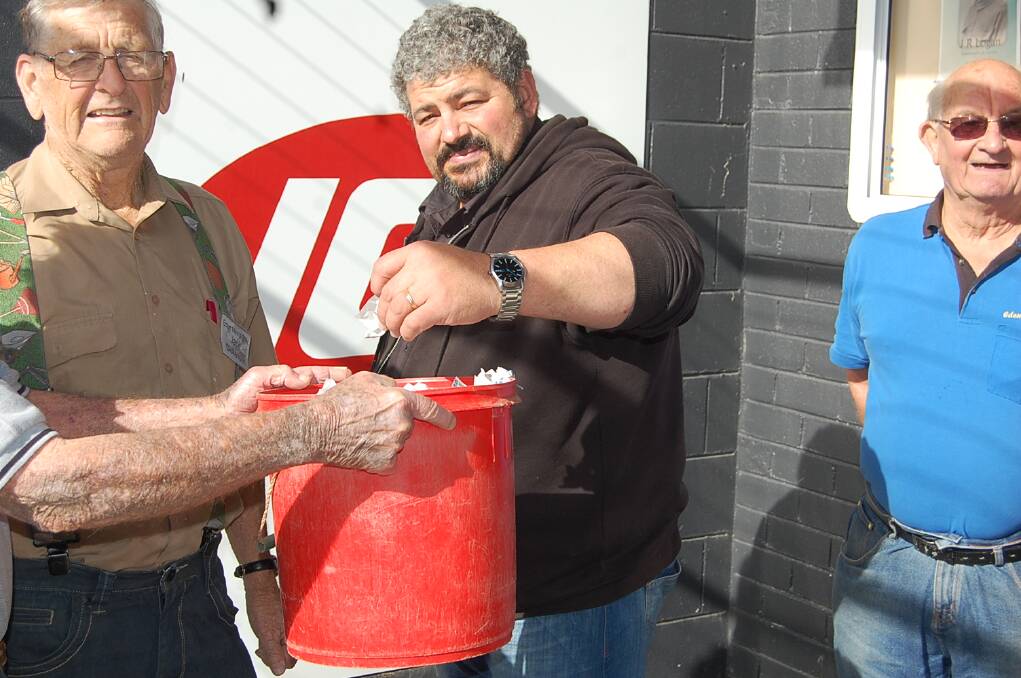 Eden IGA owner Con Castrissios draws the winning ticket for the Eden Men's Shed raffle on Wednesday morning.