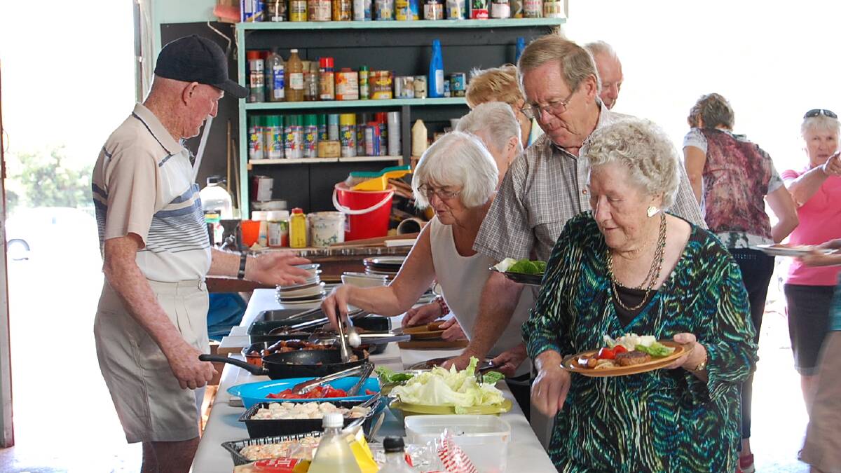 Guests of the Men’s Shed take their pick of the Seniors Week lunch spread.