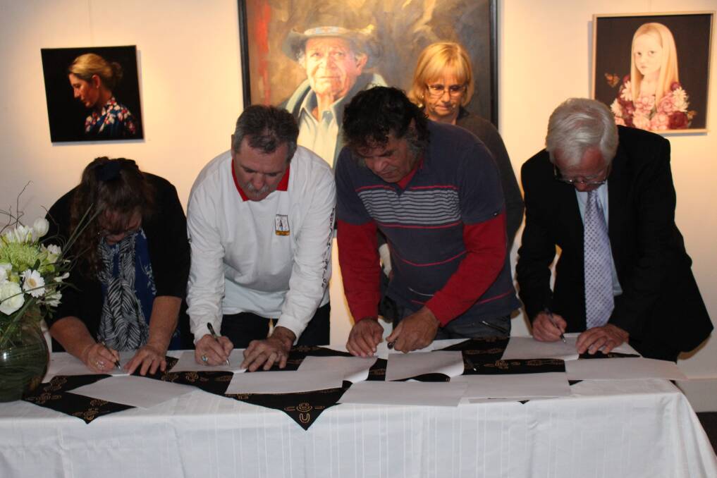 Local Aboriginal Land Council representatives Lorraine Naylor (Merrimans), Graham Moore (Bega) and Ben Cruse (Eden), along with Mayor Bill Taylor, sign the updated Memorandum of Understanding in the Bega Valley Regional Gallery, watched by Council General Manager Leanne Barnes, under the portrait of Aboriginal elder Ossie Cruse which was a finalist in the Shirley Hannan National Portrait Award.