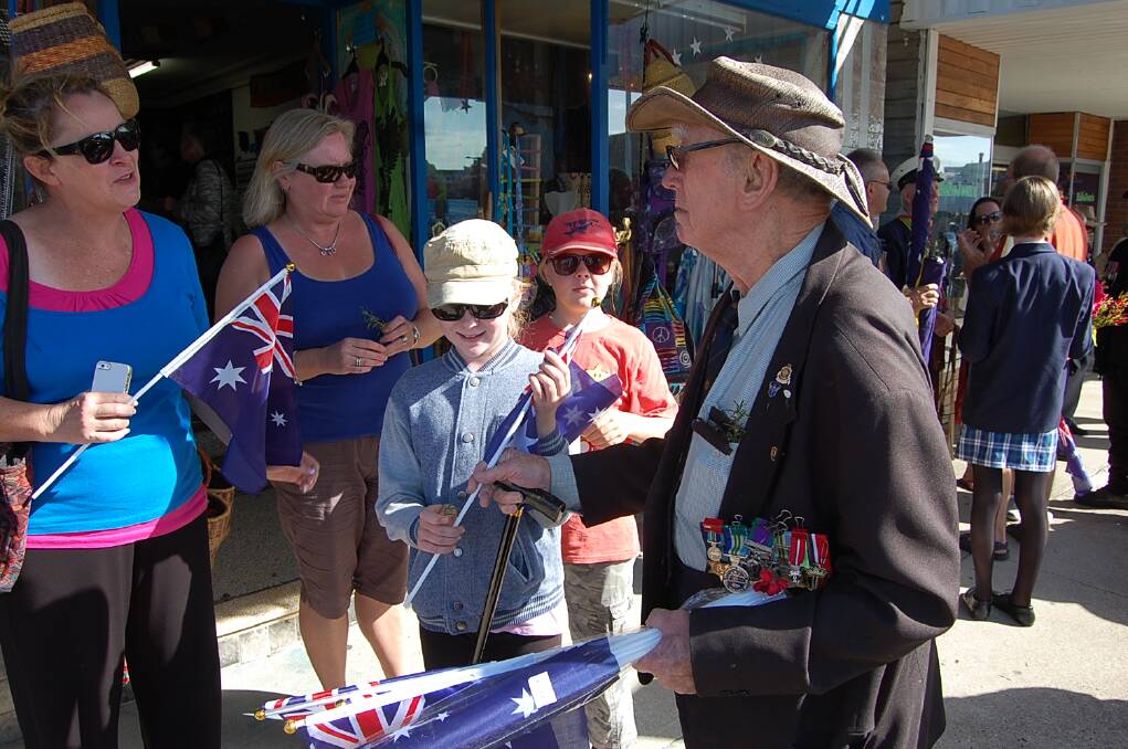 One of Eden's most senior war veterans, Artie Edwards, handing out Australian flags before the ANZAC DAy 2014 march through the town.