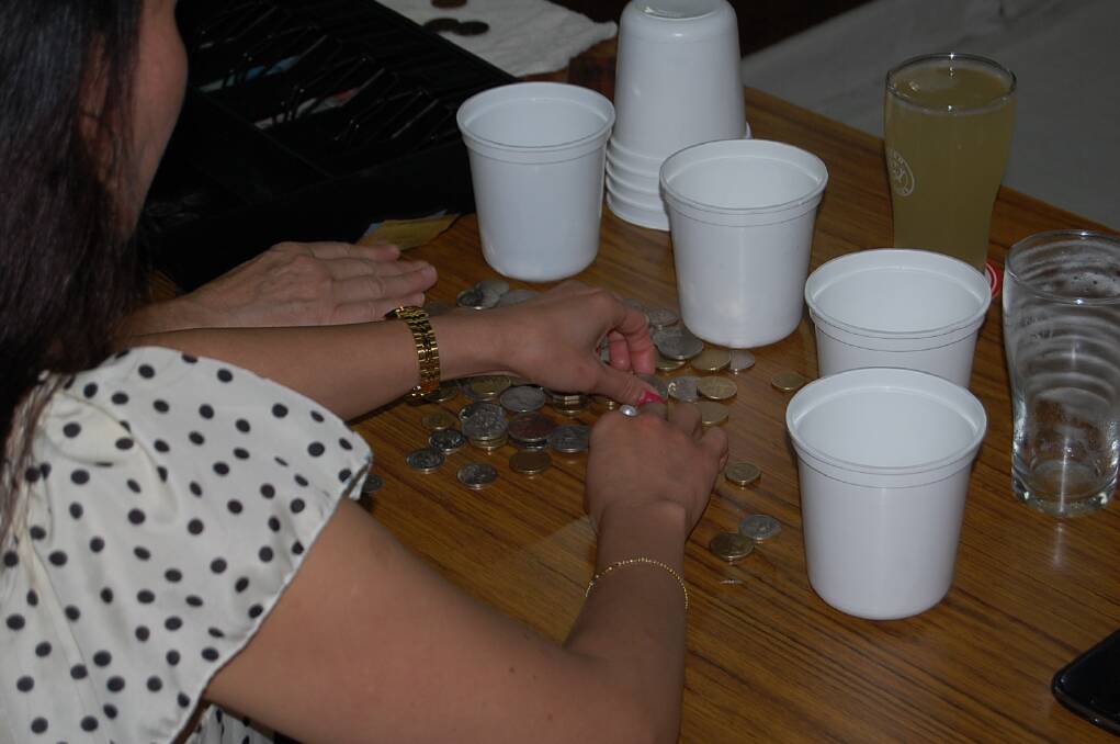 Coin donations for Legacy are sorted into cups as part of two-up at the Eden Fishermen's Club on ANZAC Day.