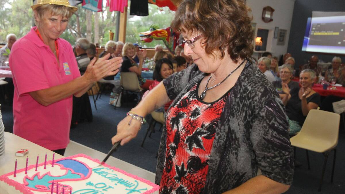 • Pat Helmore watches on as Sapphire Water Dragons founding member Jenny Kimber cuts the cake at celebrations held on Saturday. 