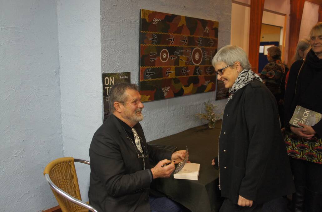 John Blay signs a copy of his new book at the launch at Jigamy on Saturday. 