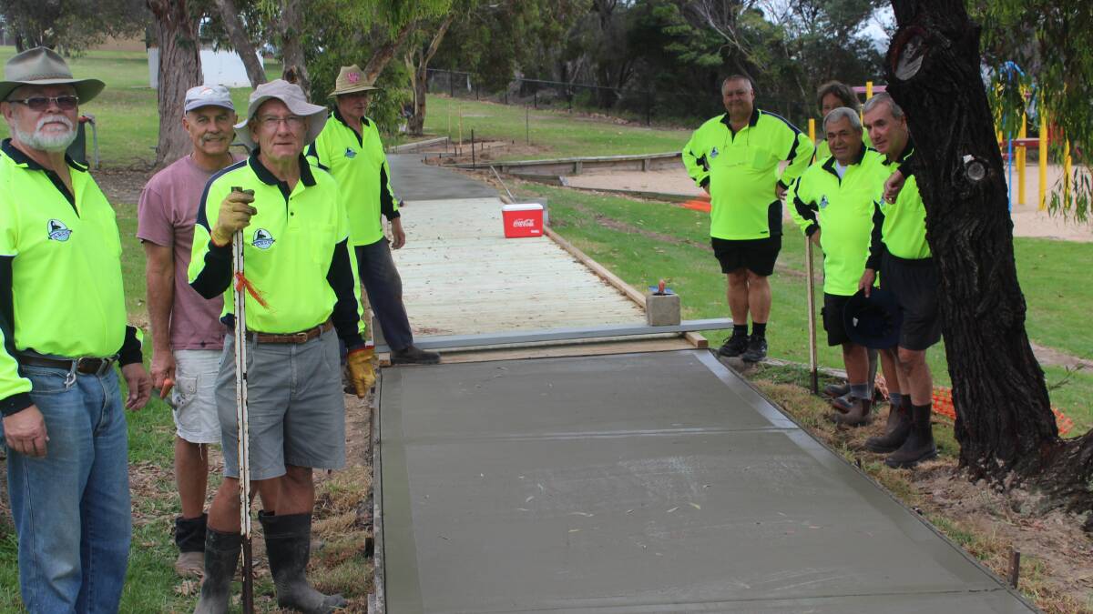 ESSCI members Steve Mahoney, Graham Gray, Harry Weatherman, John Mutch, Ken Traise, Jim Chenhall, Jeff Swane and Dave Rogers trying to stave rain away from the wet concrete at Imlay Memorial Park. Photo: Kate Liston