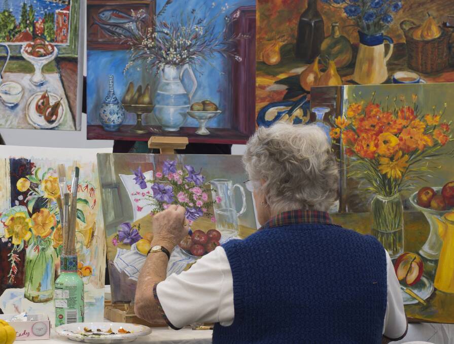 Vibrant colour: In the world of Olley - U3A’s Liz Mckay is putting the final touches on her Magaret Olley inspired painting .She is surrounded by other U3A artist’s Olley inspirations. Picture: Rachel Mounsey