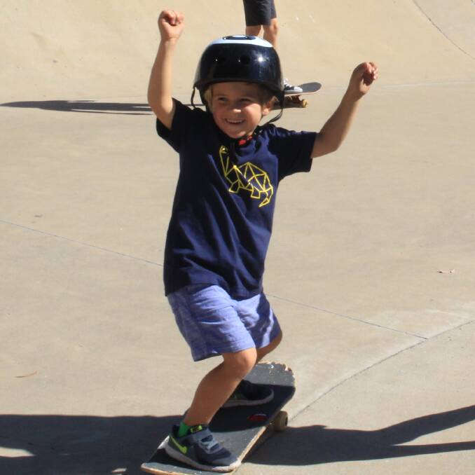 Kai Schroder, 4, throws his hands in the air and cheers with excitement at skating all by himself at the skateboard workshop in Pambula. 