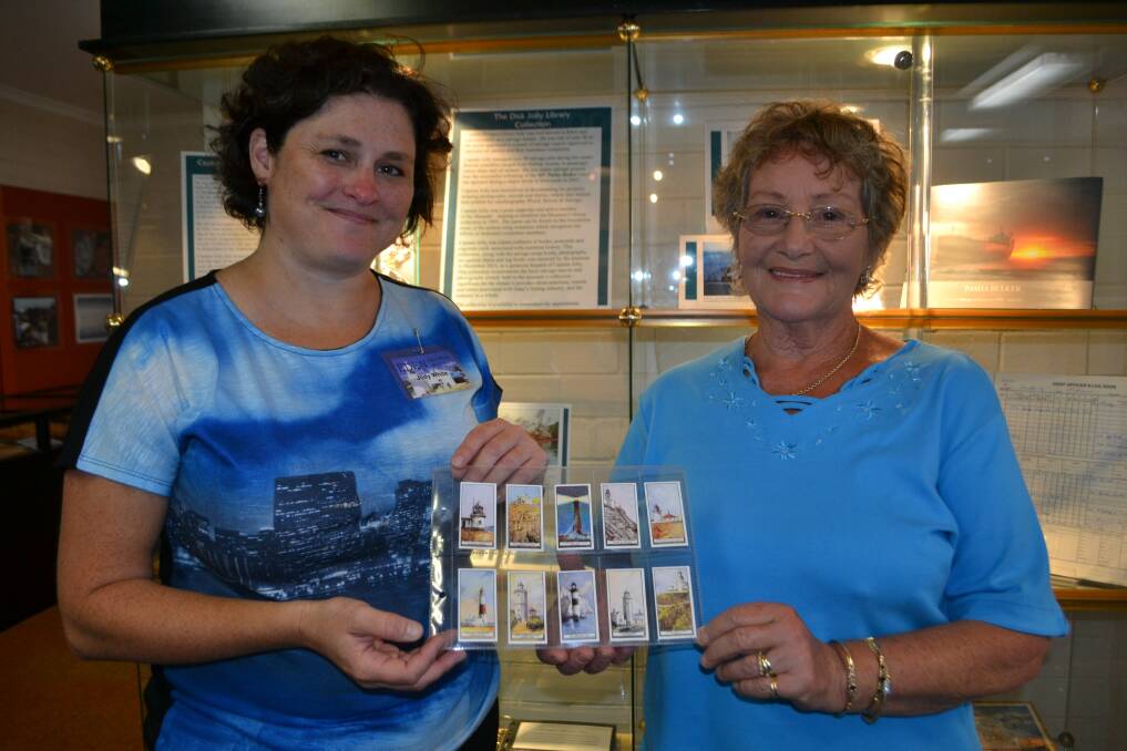 Eden Killer Whale Museum curator Jody White and Ros Warren hold up some cigarette cards from master salvage master Dick Jolly’s collection, currently being cataloged at the museum.