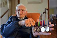 Navy veteran David Craker looks at his World War II medals on Remembrance Day. He was awarded the 1939-1945 Pacific War Medal, The Pacific Star, the Victory medal and the Australian Service medal.