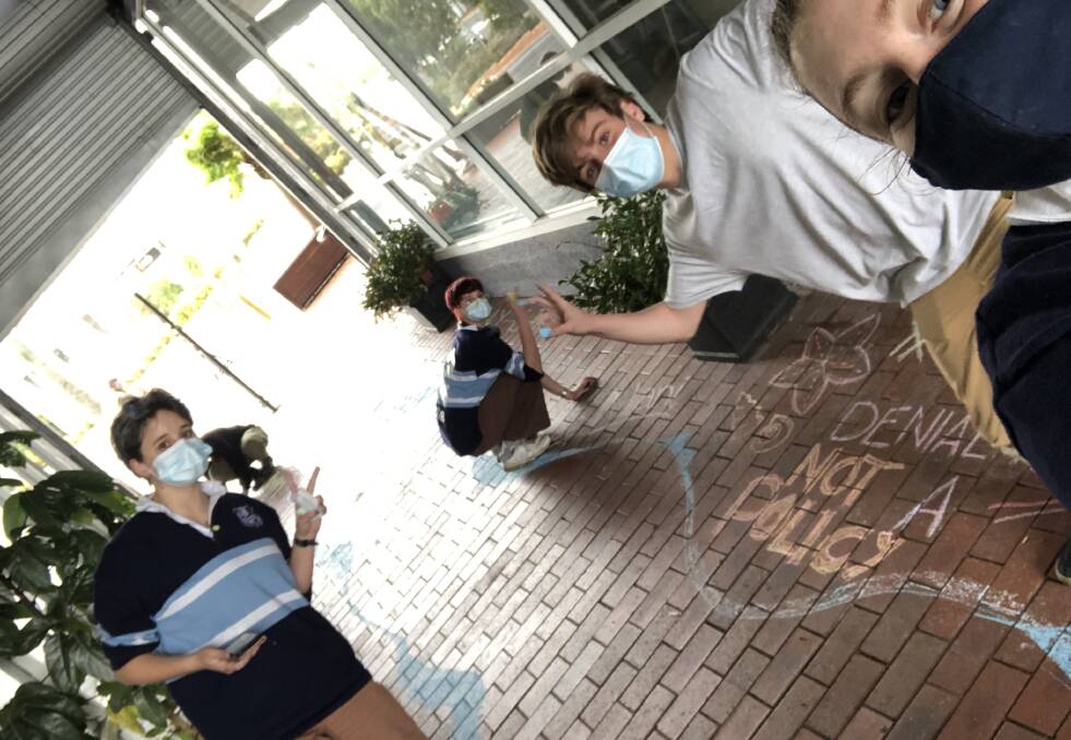 A group of Year 12 students on the Far South Coast get together in Merimbula to draw messages of climate change on the pavements of the town, for the School Strike for Climate (SS4C) on October 15. Photo supplied. 