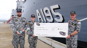 GIVING BACK TO HOME PORT: Mark Hunter hold a bottle of the Commissioning Gin, with Georgie Baldwin and Supply II Captain Ben Hissink holding a cheque for $1800 to go towards the Eden Whale Festival. Photo: Ellouise Bailey 