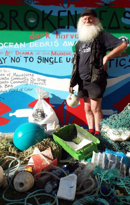 CAMPAIGN: Mallacoota arts leader Don Ashby stands among marine debris during the Easter weekend ocean awareness campaign which included the unveiling of murals and screening of a film. Pictures: Courtesy Julie Parker. 