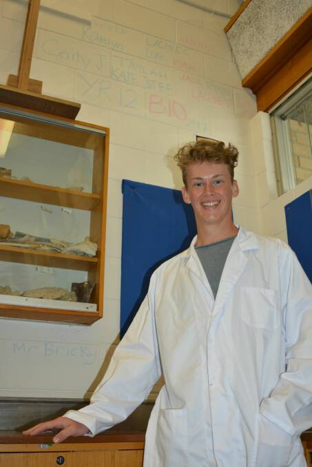 Eden Marine High School graduate Lachlan Considine in his former biology lab where he and his classmates have inscribed their names on the wall as part of an ongoing tradition.