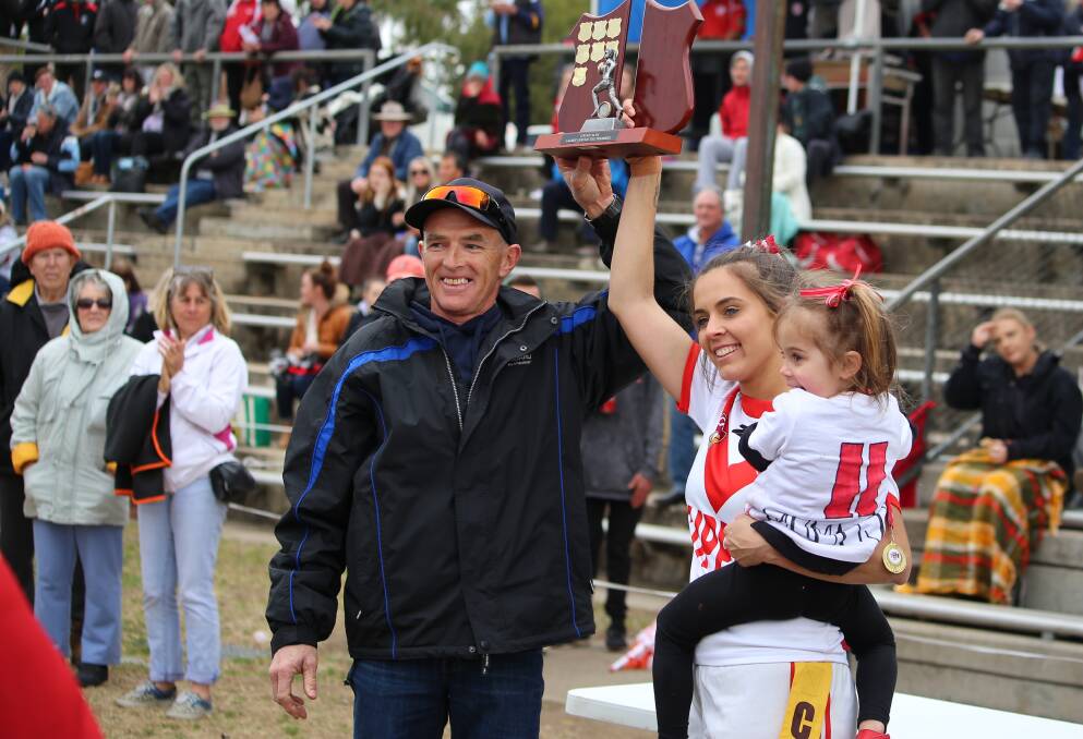 Eden Tigerettes coach Peter Mitchell and captain Jacqueline Keevil-Scott with her daughter hold aloft the Group 16 2018 premiership trophy.