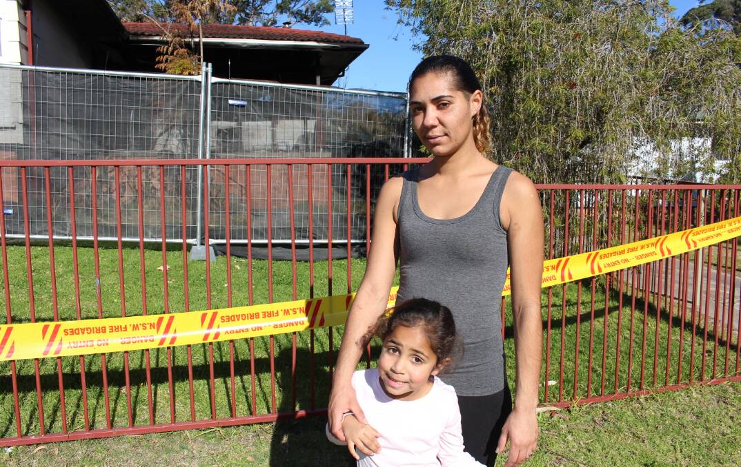 Jolene Brindle and her daughter Nalanya in front of their blackened home on Moorhead Street, Eden.