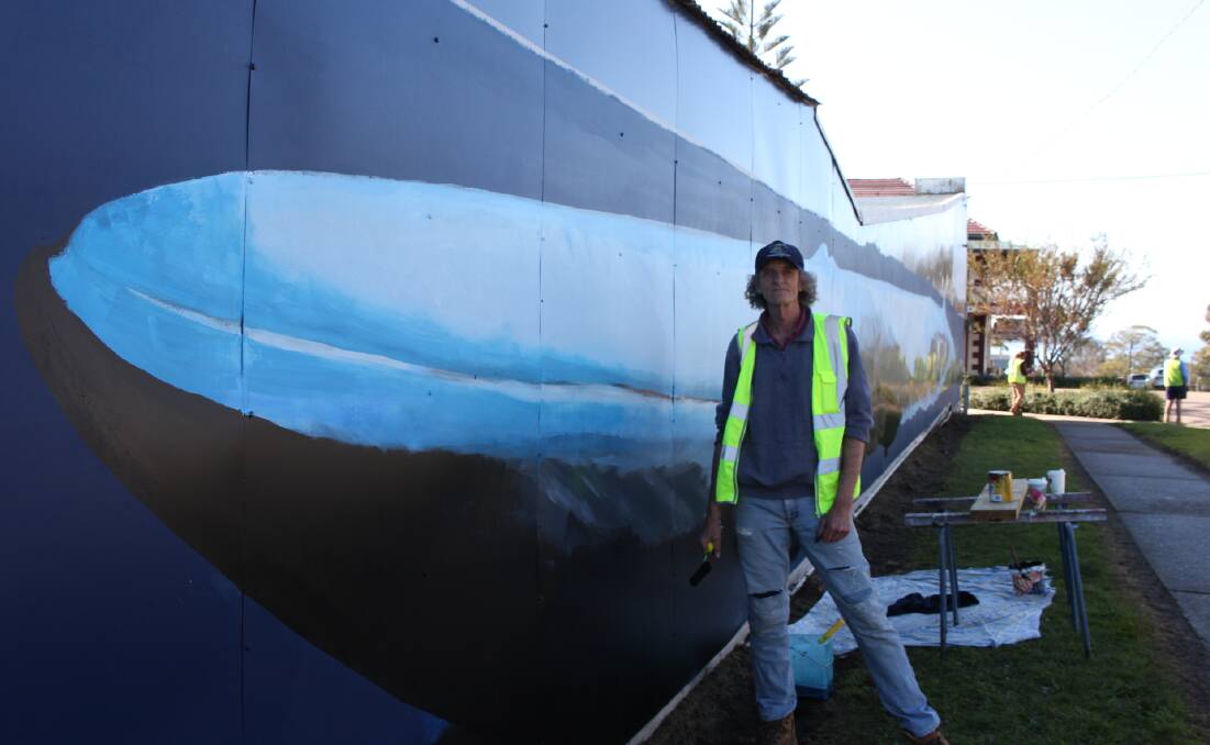 Brett Ralph working on the mural of the 97-foot blue whale.