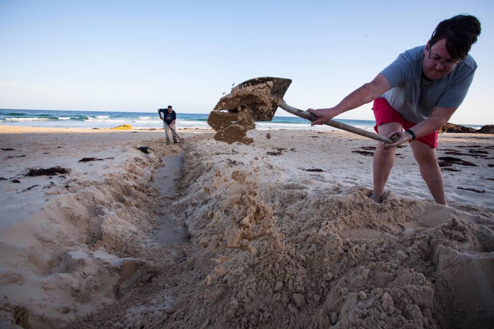 Locals fill in the tourist made trench at Betka beach, Mallacoota. Photo: Rachel Mounsey