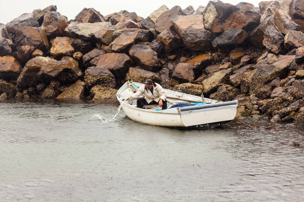 Mick Bell tipping water out of his netting boat during Tuesday afternoons downpour. Photo: Rachel Mounsey