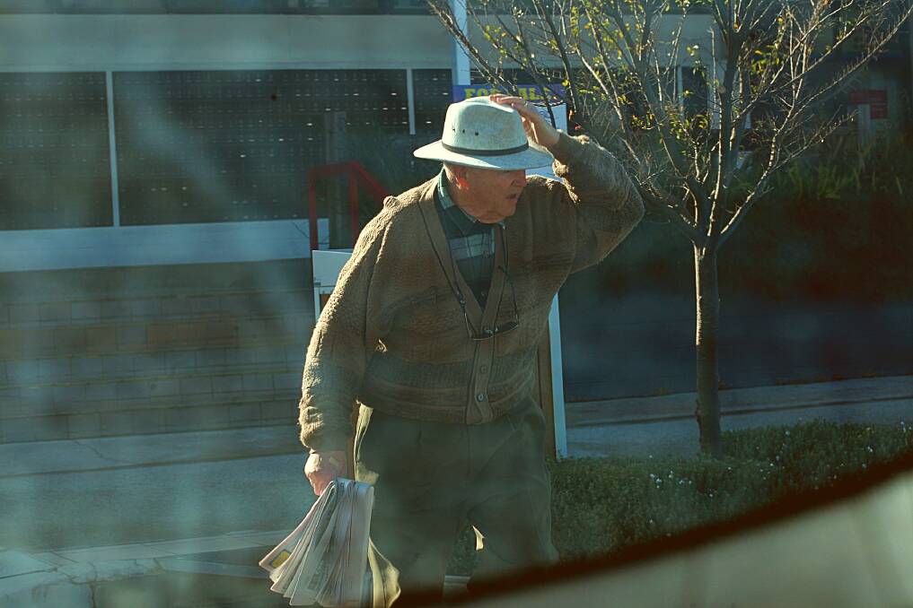  A man grabbing onto his hat during strong winds in Eden this morning. Photo: Rachel Mounsey