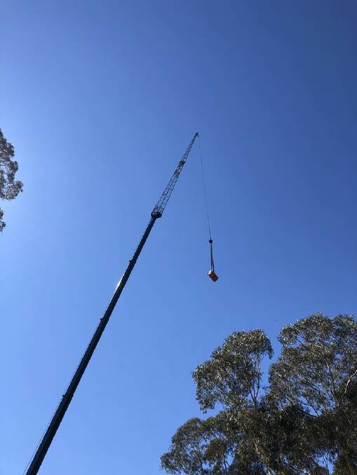 A crane lifts one of the drums out of bushland. Photo: NSW Fire and Rescue