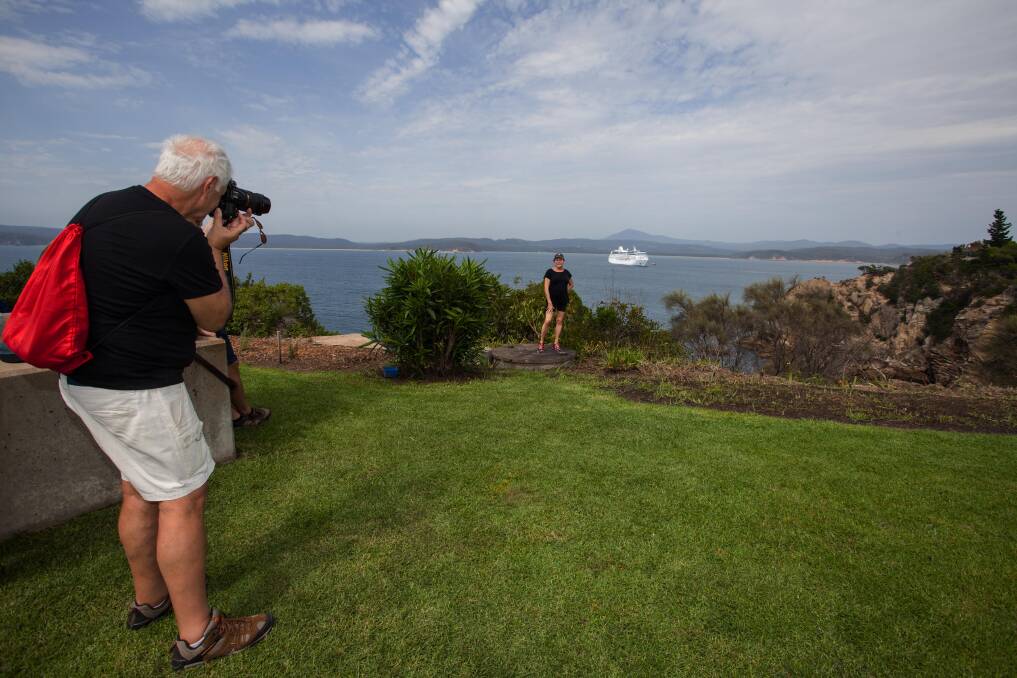 Happy snappers: Cruise tourist Larry Baum takes a photo of his wife with the Oceania Regatta   in the background whilst on 'Picture Perfect' tour of Eden. Photo: Rachel Mounsey
