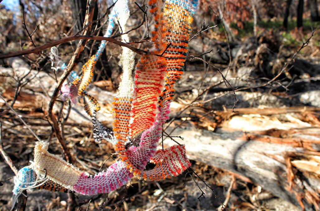 One creative local brought colour to the ash by "yarn bombing" an area of burnt bush near the entrance to Tathra and Thompsons Drive in May last year. Picture: Alasdair McDonald
