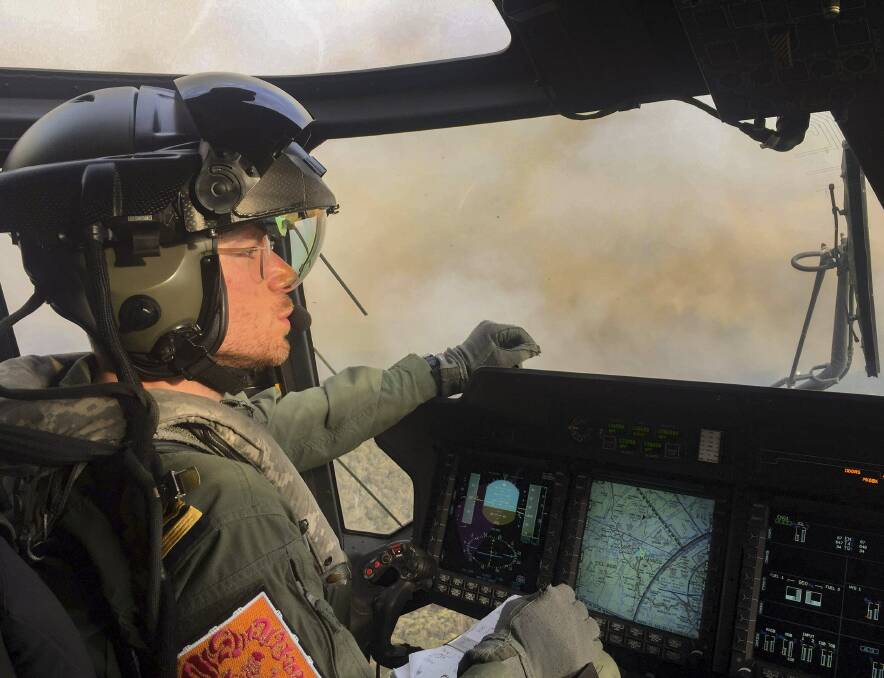 FIRE ZONE EXPERIENCE: Royal Australian Navy Pilot Lieutenant Commander Nick Grimmer, in an 808 Squadron MRH90 Taipan Military Support Helicopter over the Grose Valley bushfire in the Blue Mountains National Park. Photo: Brett Kennedy