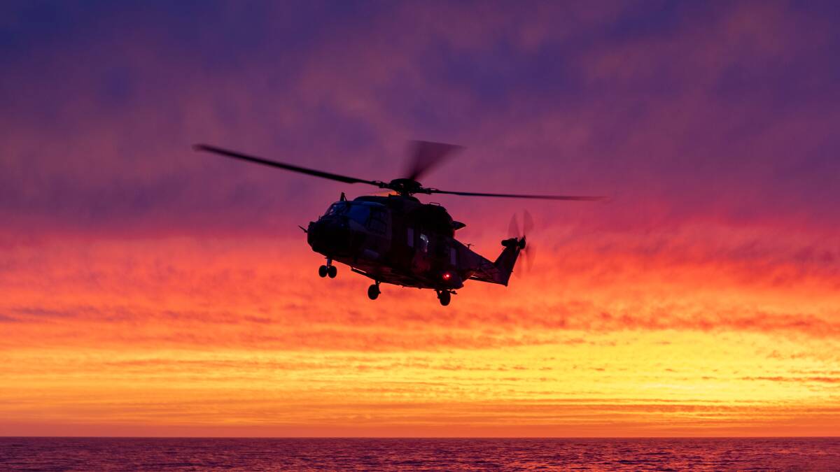 HMAS Choules MRH-90 Maritime Support Helicopter makes a final approach to land at sunset during the ships transit along the east coast of Victoria. Photo: Shane Cameron