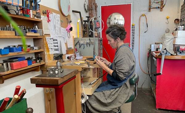 Gabrielle McGrath focuses on a piece at her workbench wear she creates wearable art.