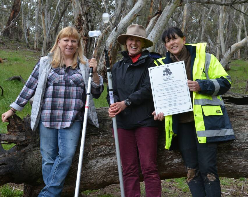 Two new members of the LAOKO mange treatment team, Kathy Healey and Micky Watts, with the mange team co-ordinator Elena Guarracino with a mange sign to warn members of the public that wombats are being treated for mange in the area.