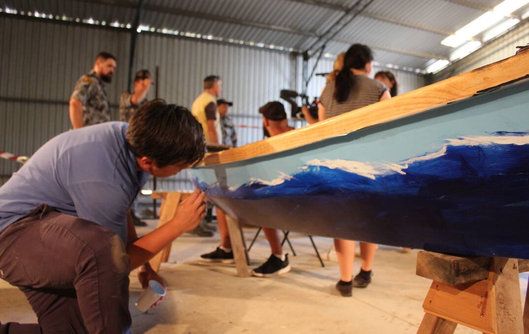 Eden Marine High student Dre Wicks hard at work painting his canoe. Photo: Leah Szanto