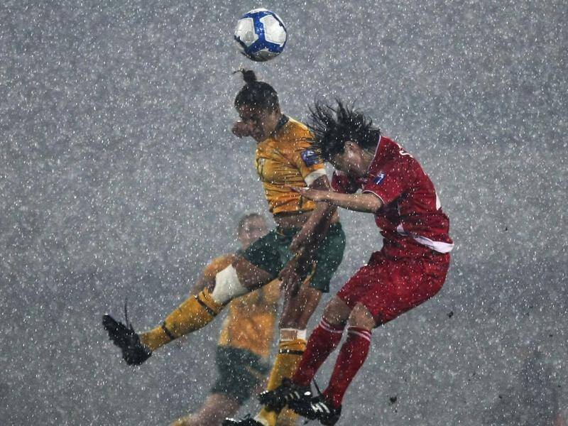 Kyah Simon fights for the ball in the 2010 Asian Cup final against N Korea played in pouring rain.