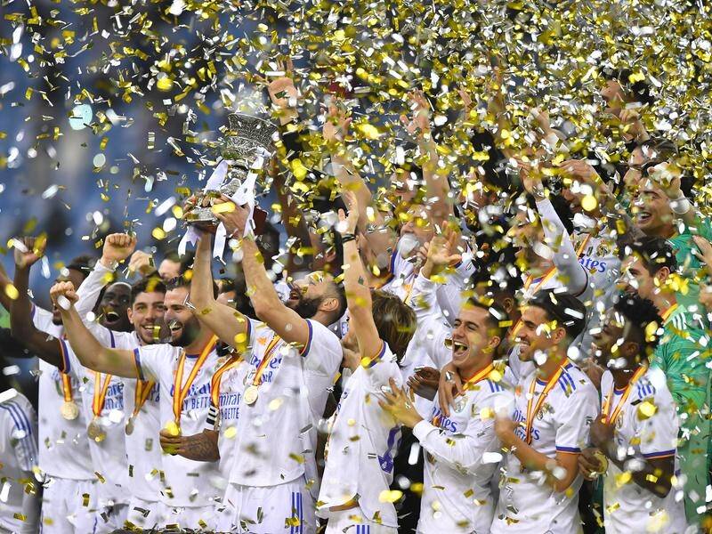 Real Madrid captain Karim Benzema lifts the Spanish Super Cup trophy as his teammates celebrate.