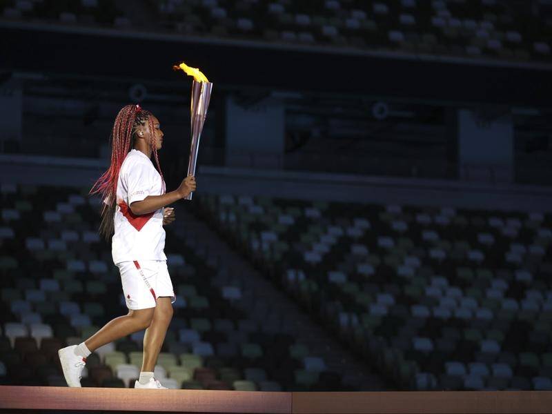 Naomi Osaka carries the torch before lighting the cauldron in Tokyo's Olympic Stadium.