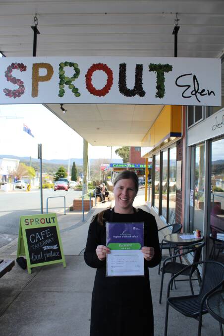 Sprout Eden employee Abby Williams holds up the business' Scores on Doors certificate.