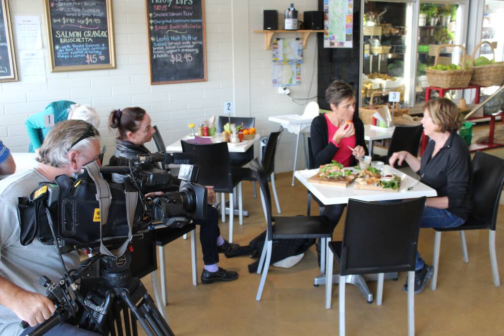 What’s Up Downunder host Michelle Pettigrove (table, left) interviews Sprout Eden fresh produce manager Barbara Greenwood (table, right), filmed by Phil Conquest and producer Liz Kefford looks on.