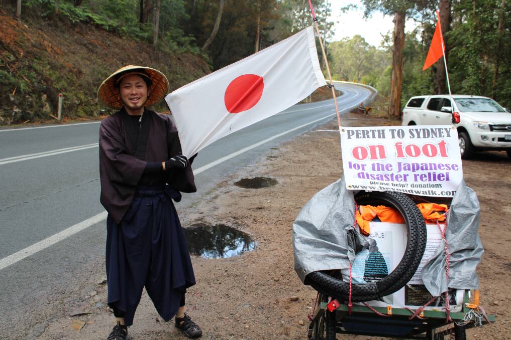 Japanese man Yuuichi Iwata stops at the Quarantine Bay bends en route to South Pambula on Wednesday. Yuuichi is entering the home stretch of a marathon charity walk from Perth to Sydney, raising funds for Japanese tsunami relief.