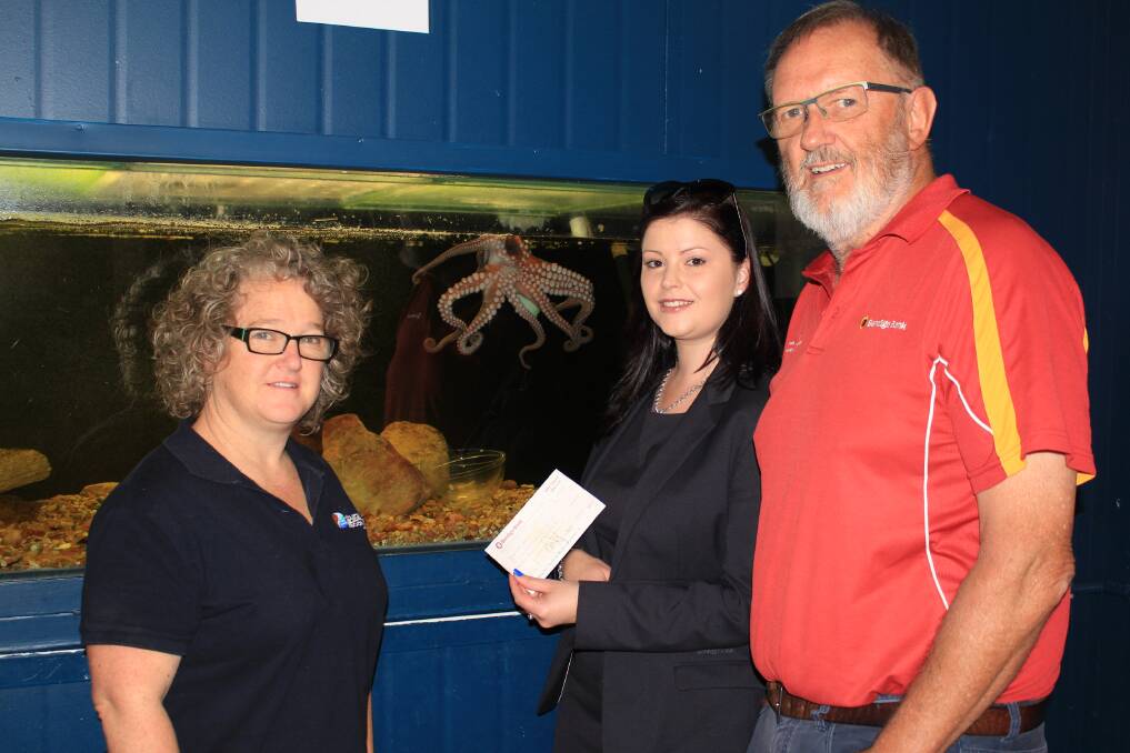 Grateful: SCMDC manager Kerryn Wood receives a cheque from Pambula Community Bank's Sandy Spain and Colin Dunne with a very friendly octopus named Adele saying hello in the background. Picture: Melanie Leach