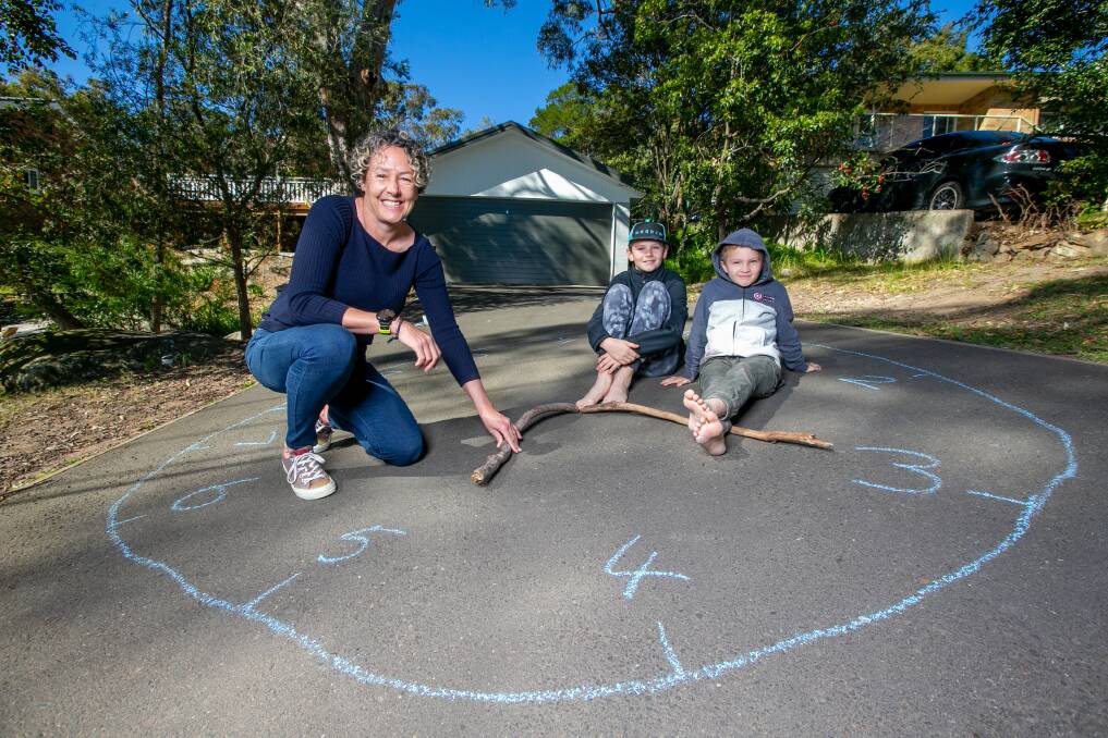 LOCKDOWN LEARNING: Susie Campbell and her sons Thomas, 11, and Patrick, 8, learning to tell time on the driveway. Picture: Geoff Jones